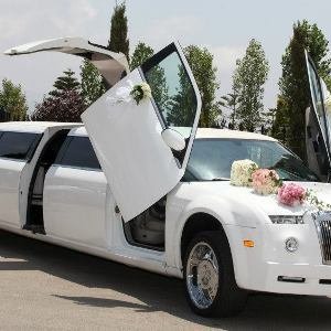 Exterior of white Phantom Luxury Limousine with a door that opens upward decorated with wedding flower bouquet