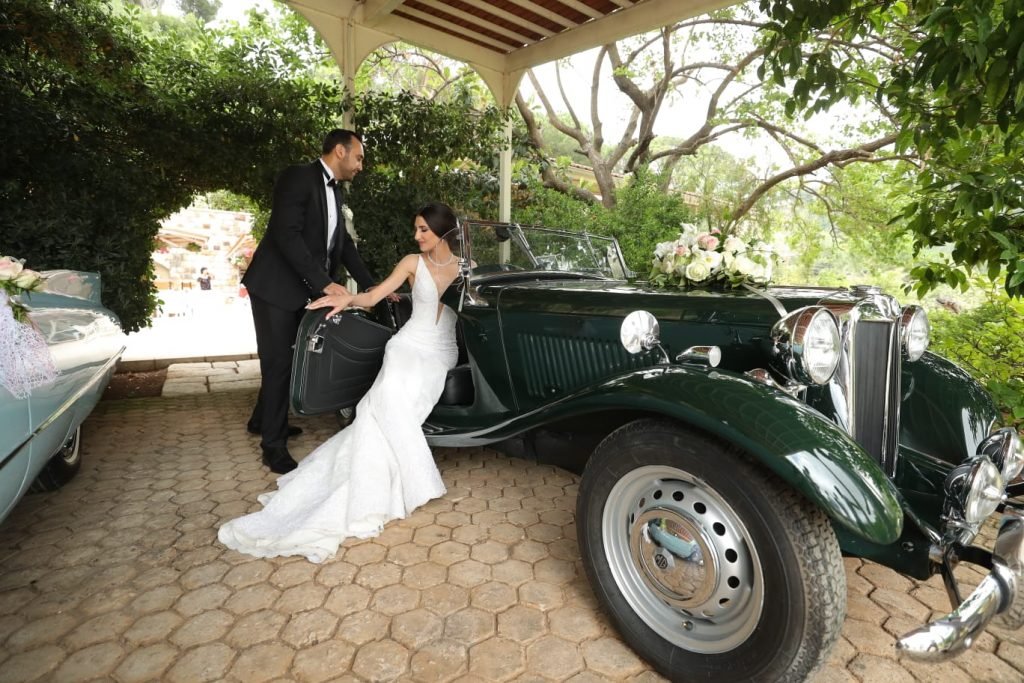 MG 1949 Roadster color dark green with the bride and groom posing next to it