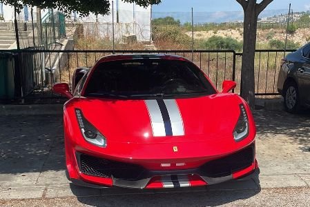 The red Ferrari Model Spider color red parked under a tree