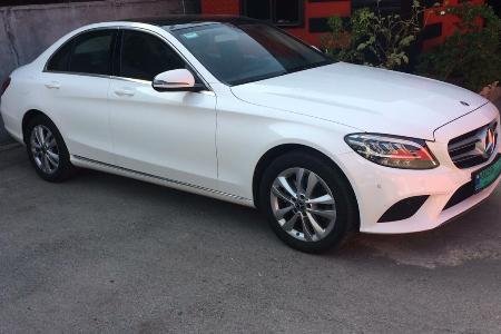Luxury white Mercedes parked in front of an amazing bush