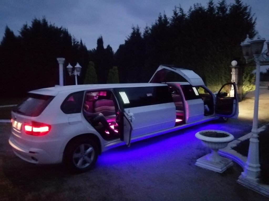 BMW X5 limo at night with all doors open and colorful led lights inside