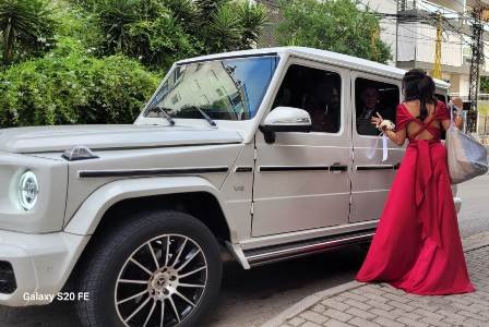 White G class along with a woman in long red dress