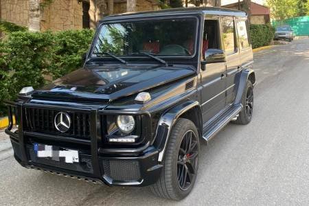 Black G Class in a luxury residential area with greenery around