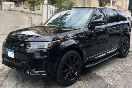 Black luxury Range Rover Sport front angle with tree in background