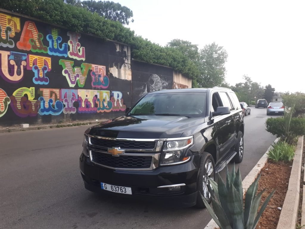 Luxury Tahoe 2020 black parked beside a colorful wall in a luxury area in beirut showing the left side of the car
